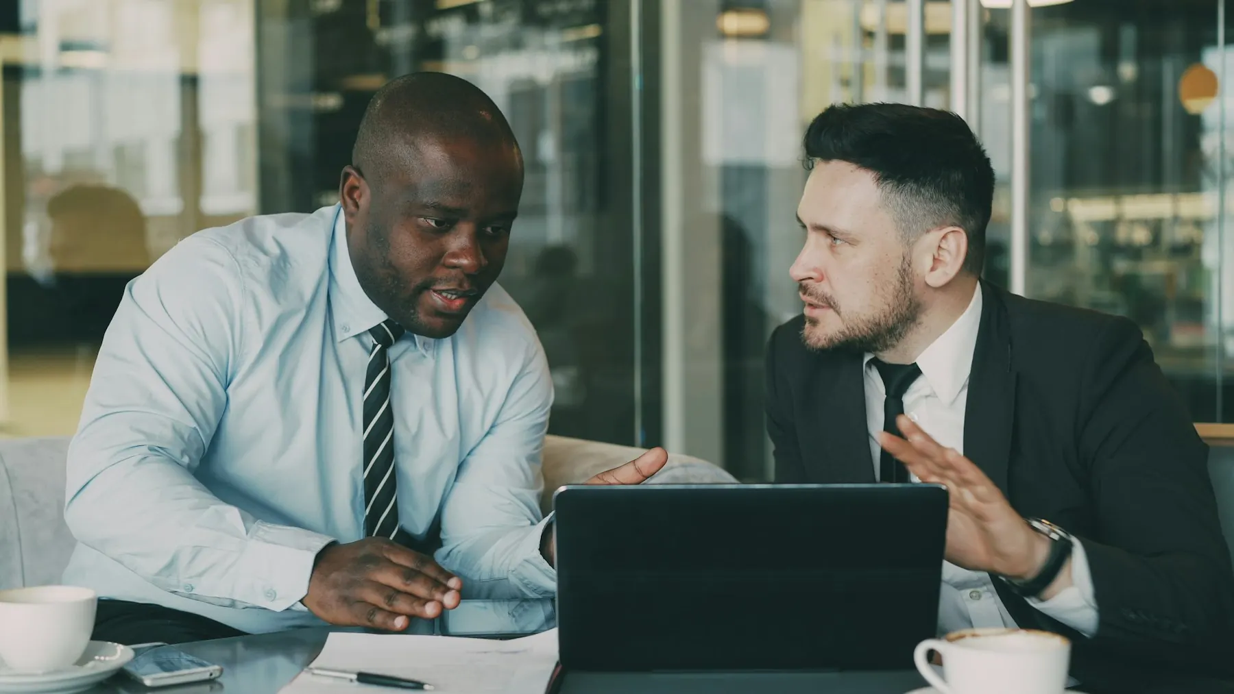 Two professionals reviewing documents in a sunlit meeting room